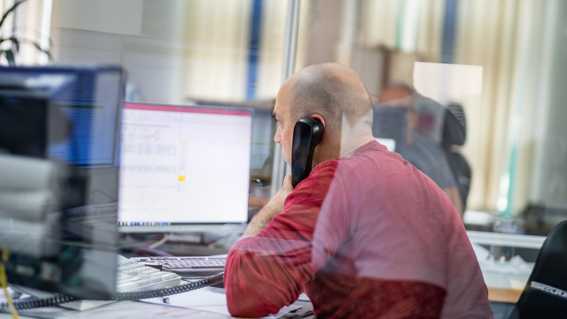 Ein Mitarbeiter sitzt am Schreibtisch und telefoniert mit Kunden.